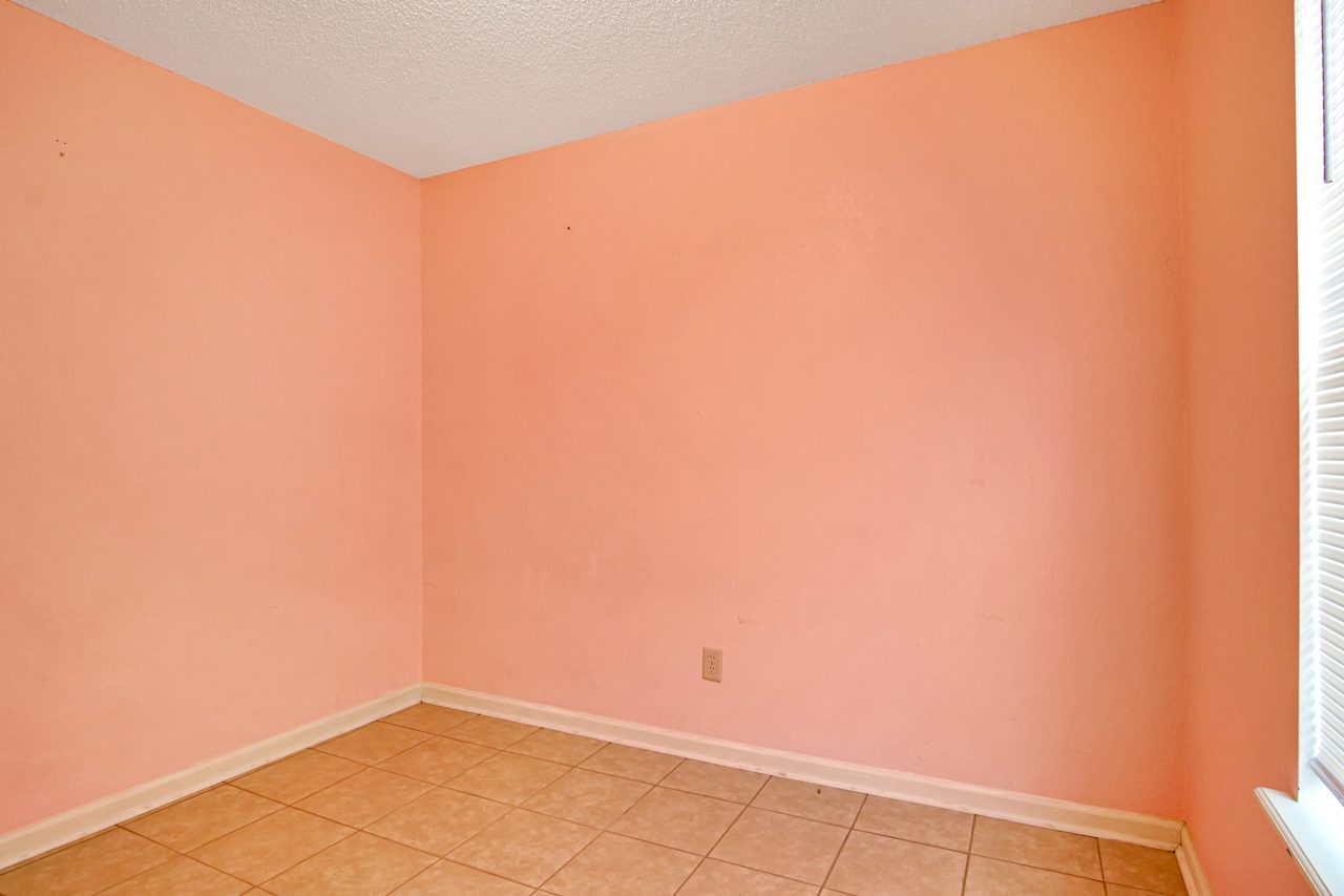 Photo of peach colored 3rd bedroom featuring white ceiling, window with white grid and white blinds, and lightly colored tile  at 2709 Oak Park Court, Tallahassee, Florida 32308