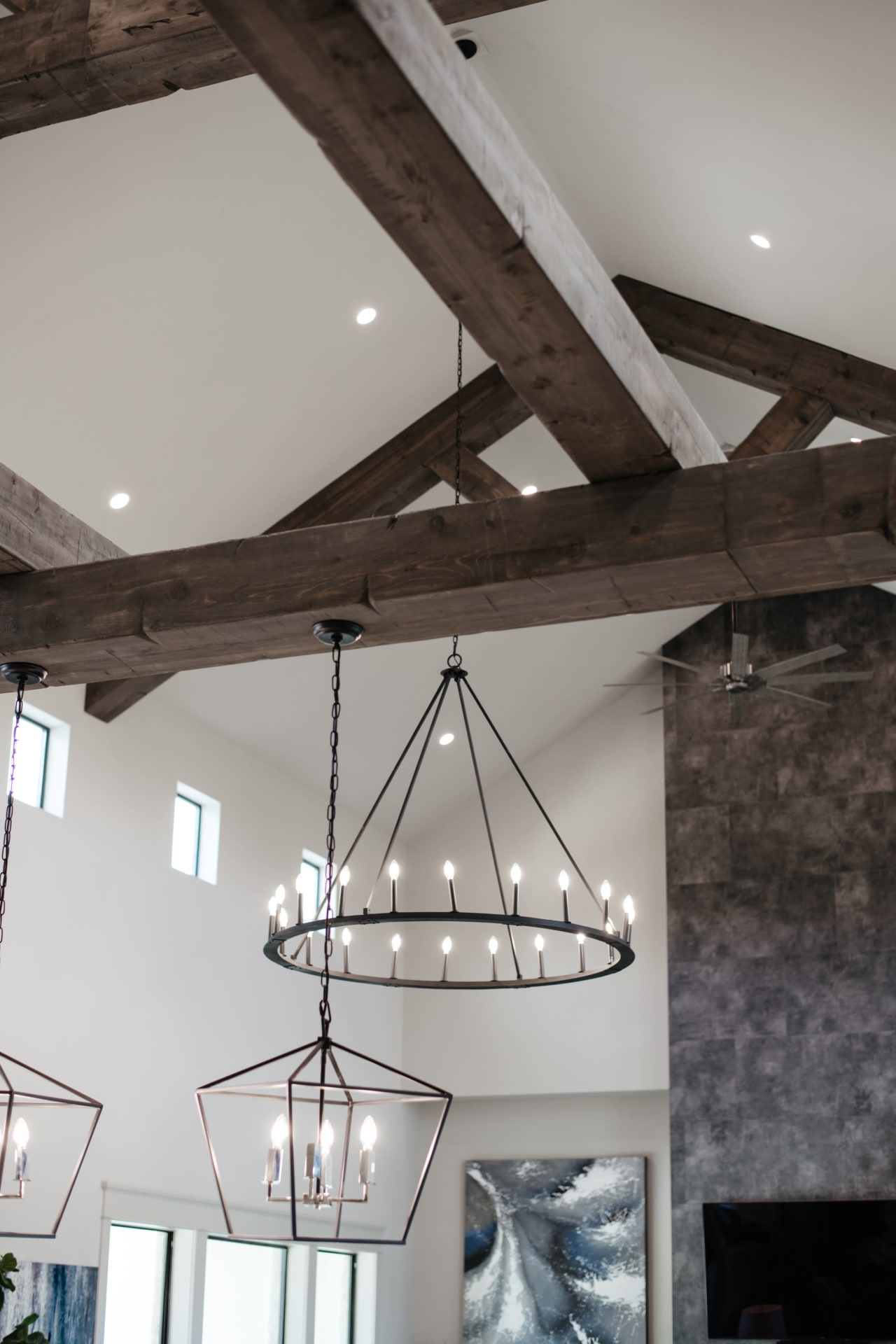 A large chandelier hangs from a wooden beam in a living room.