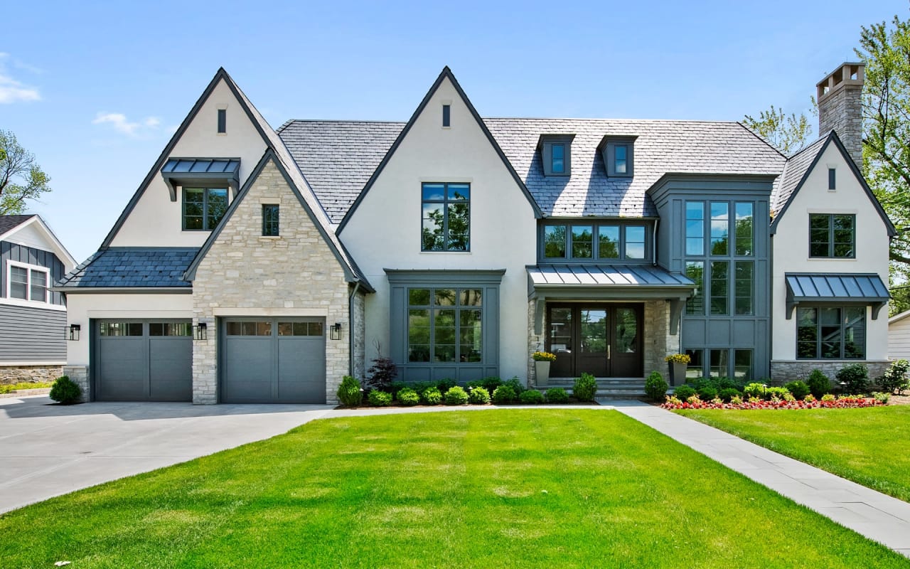 A large white house with a lot of windows. The house has a slate roof and two attached garages.