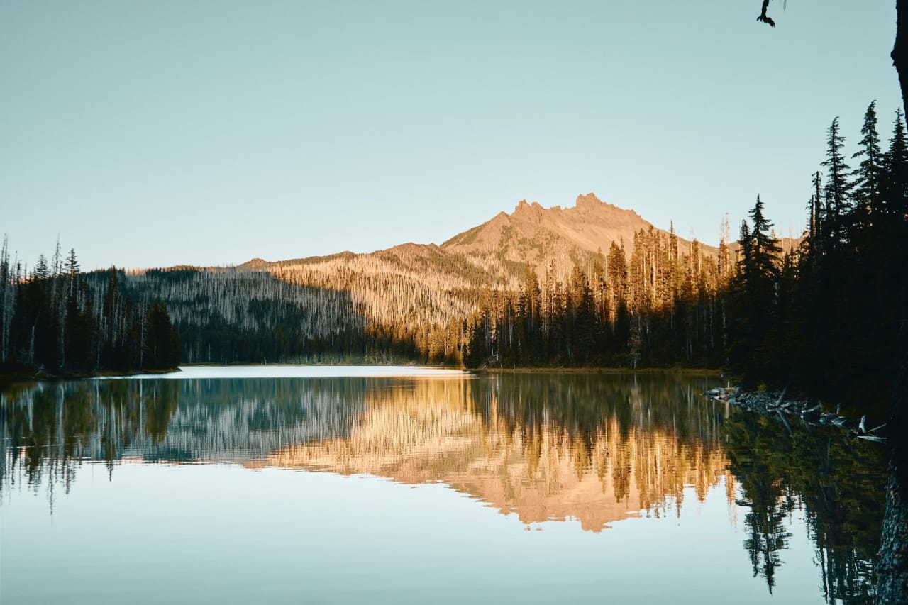 A scenic view of Northern Forest Lake, Oregon, with a mountain range in the background.