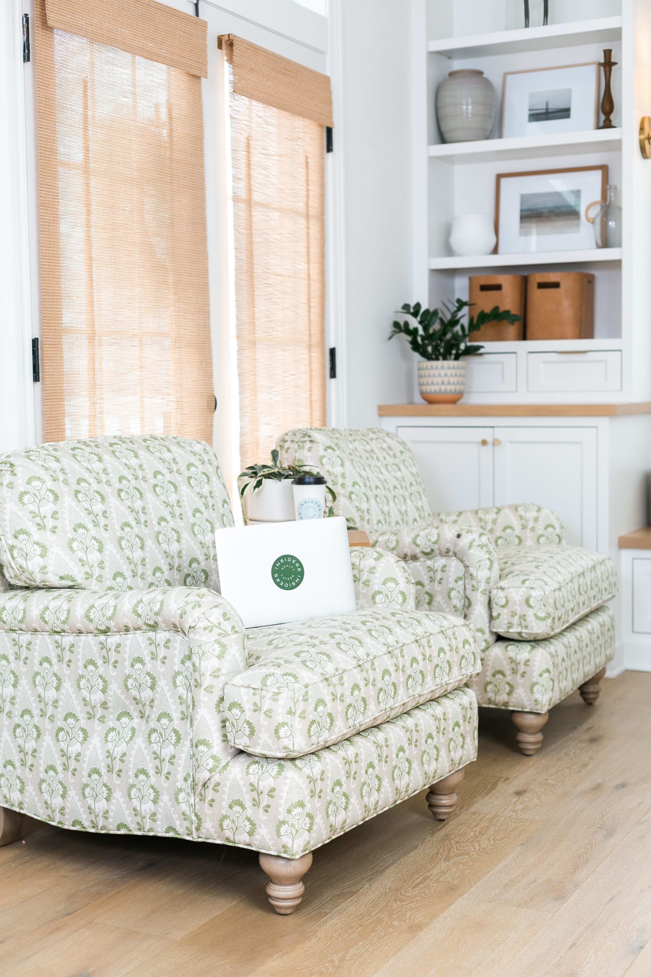 A living room setting with two chairs, a table with a laptop on it, and a potted plant in the background.