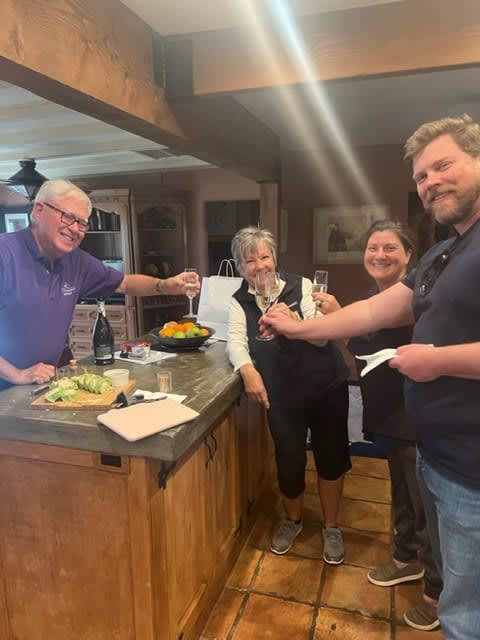 Four adults gather around a kitchen island with food and drinks.