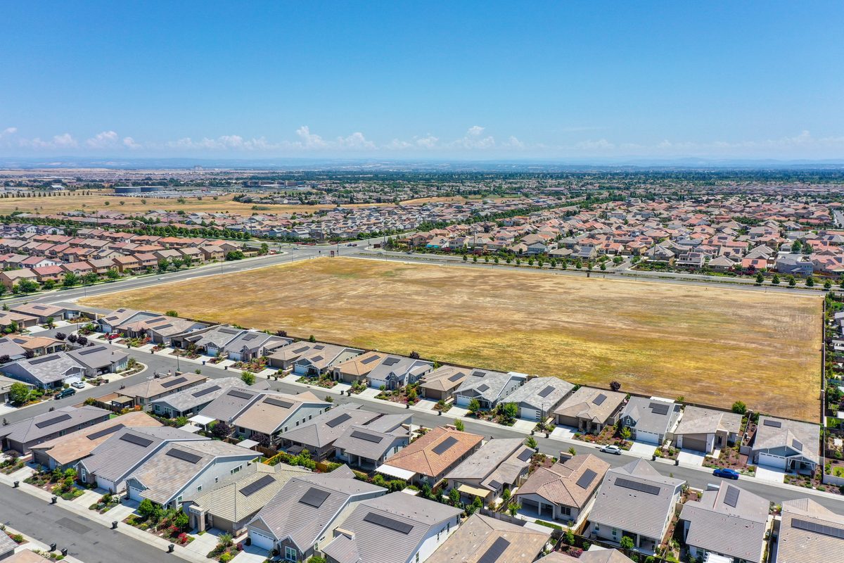 Aerial view of a new-construction subdivision in Placer County, California, with an undeveloped lot awaiting the next phase of building.