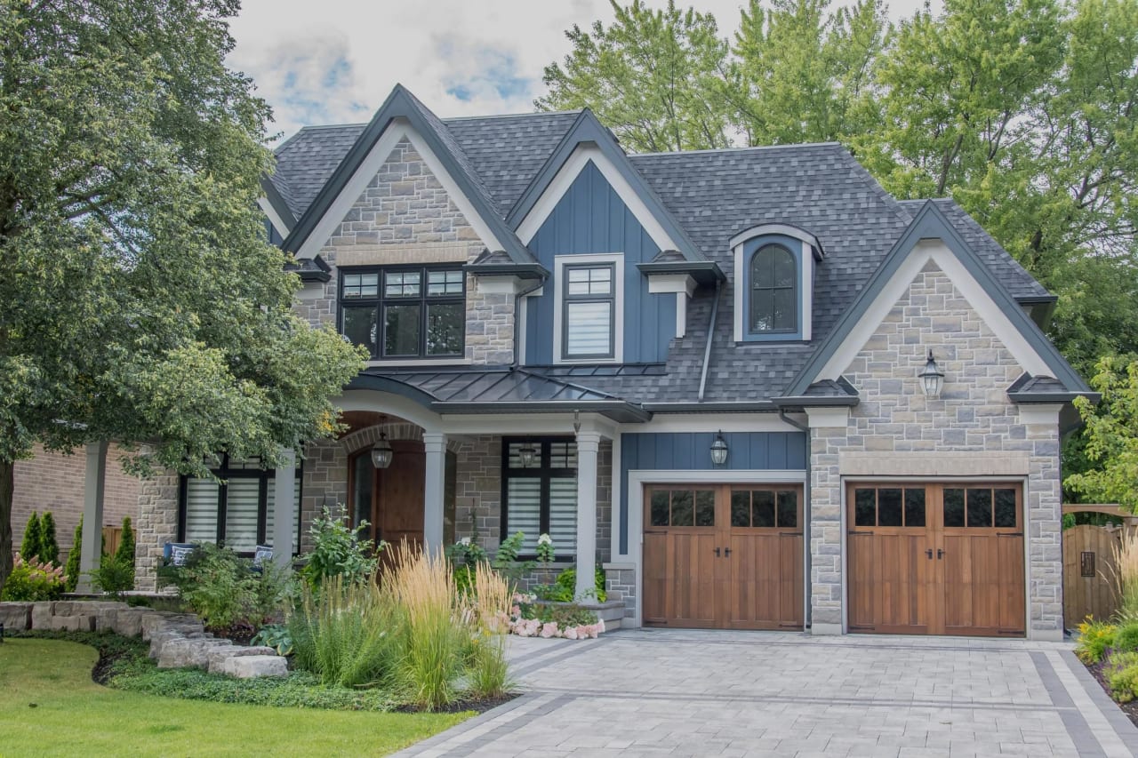 A two-story house with gabled roof, multiple windows with black frames, and a wooden front door