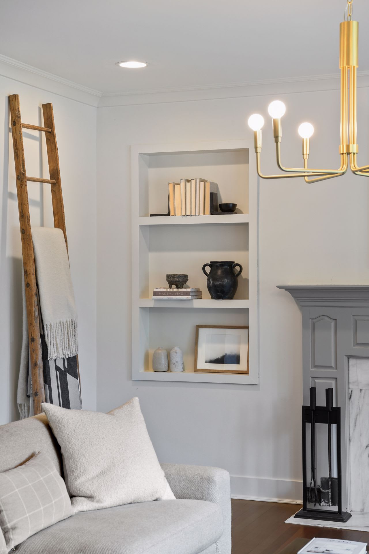 A living room interior with a white couch, a bookshelf, and a wooden ladder leaning against the wall.