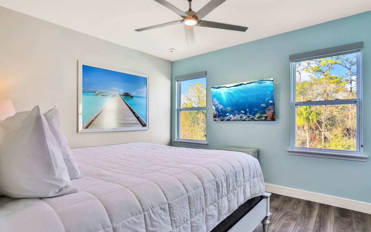 A bedroom with a bed next to two windows.