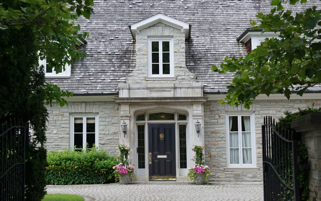 A large stone house with a black front door. The house has a slate roof and dormer windows.