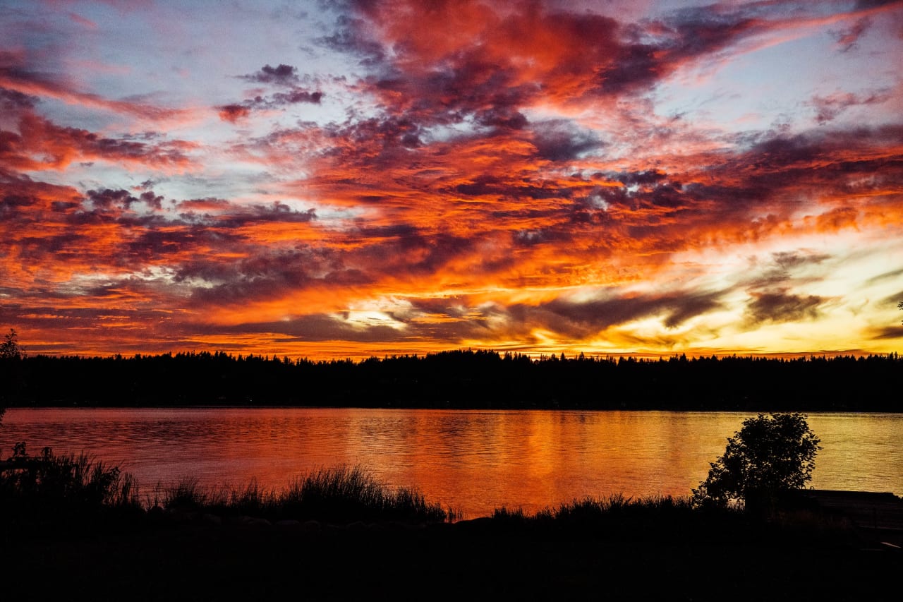 A sunset over a lake with trees in the background