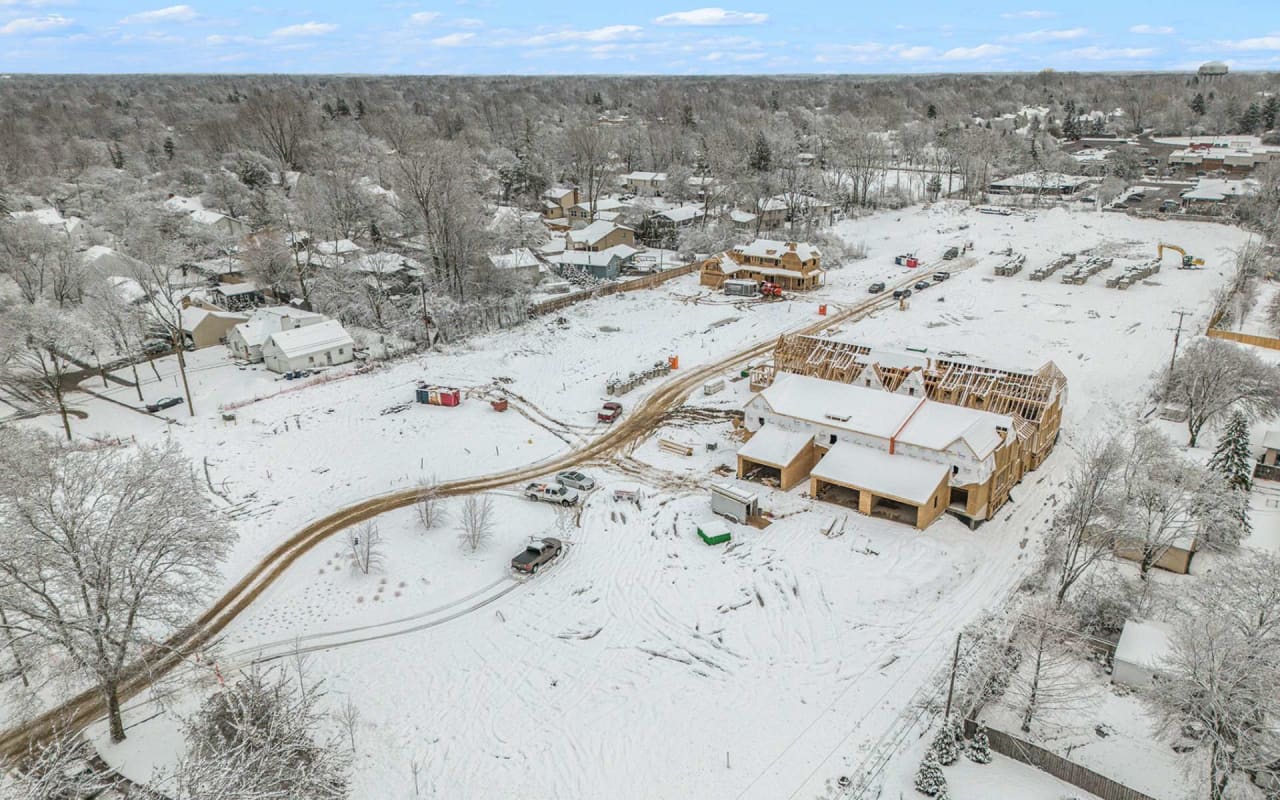 An aerial view of a new home under construction in a snowy residential area.