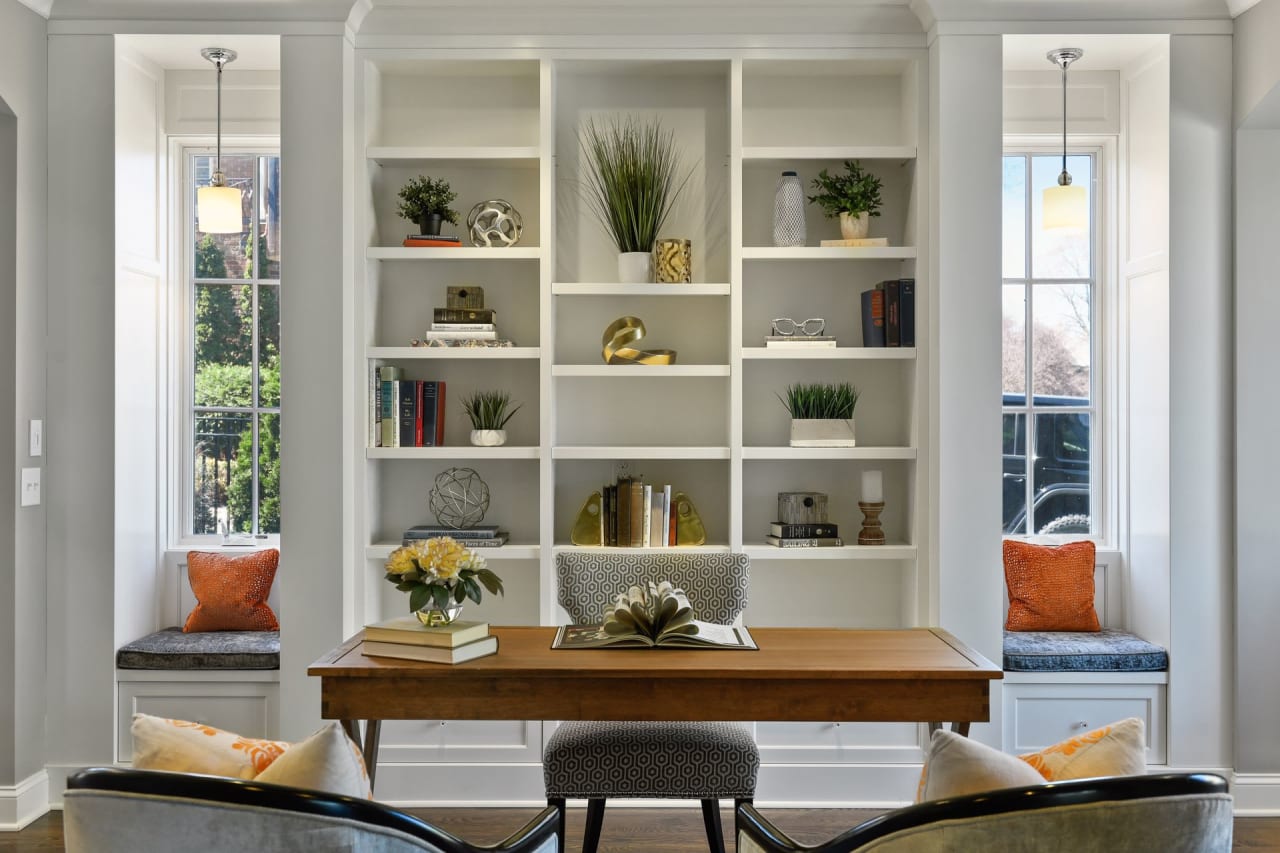 A home office with built-in shelves and a window seat.