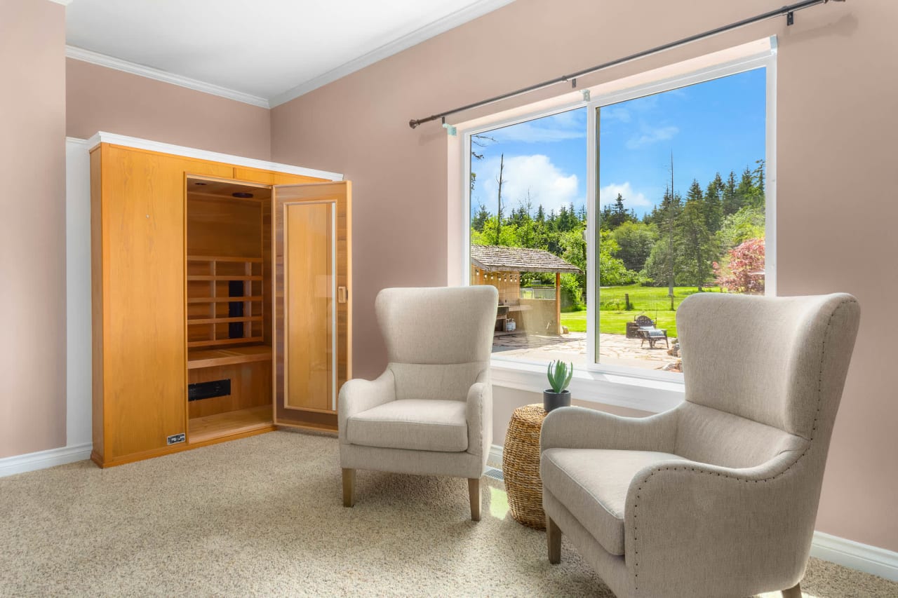 A cozy sitting area with two armchairs facing a large window overlooking a lush green landscape