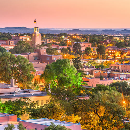 An aerial view of a city at sunset with buildings of different shapes and sizes.