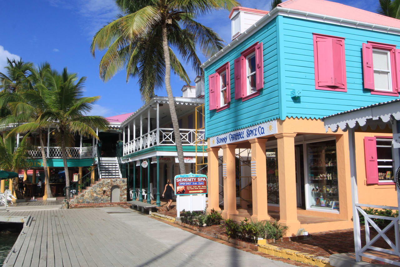 a colorful row of buildings along a wooden boardwalk with palm trees in the background