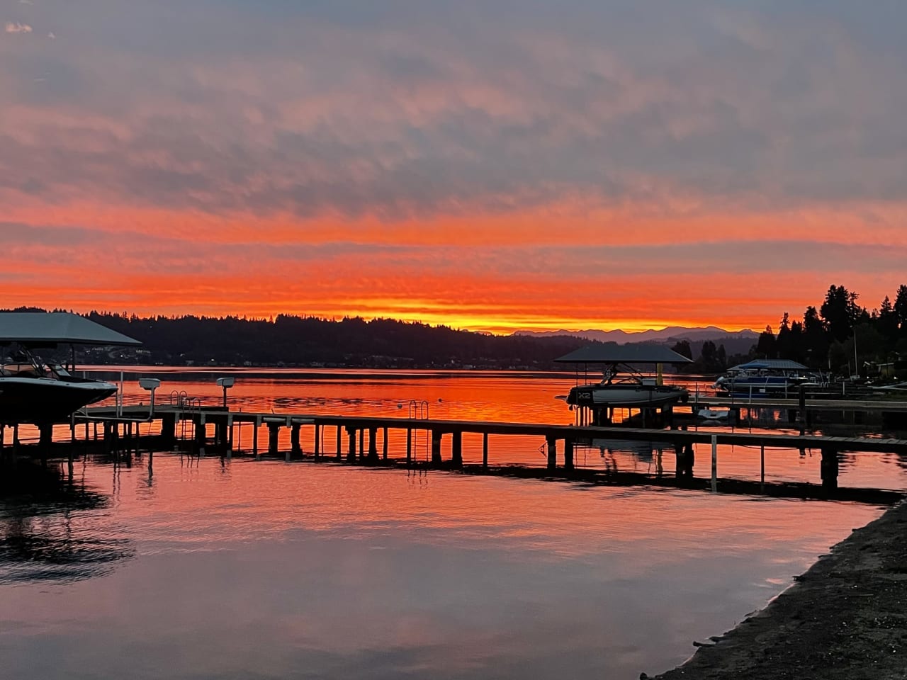 A sunset over a lake with a dock in the foreground