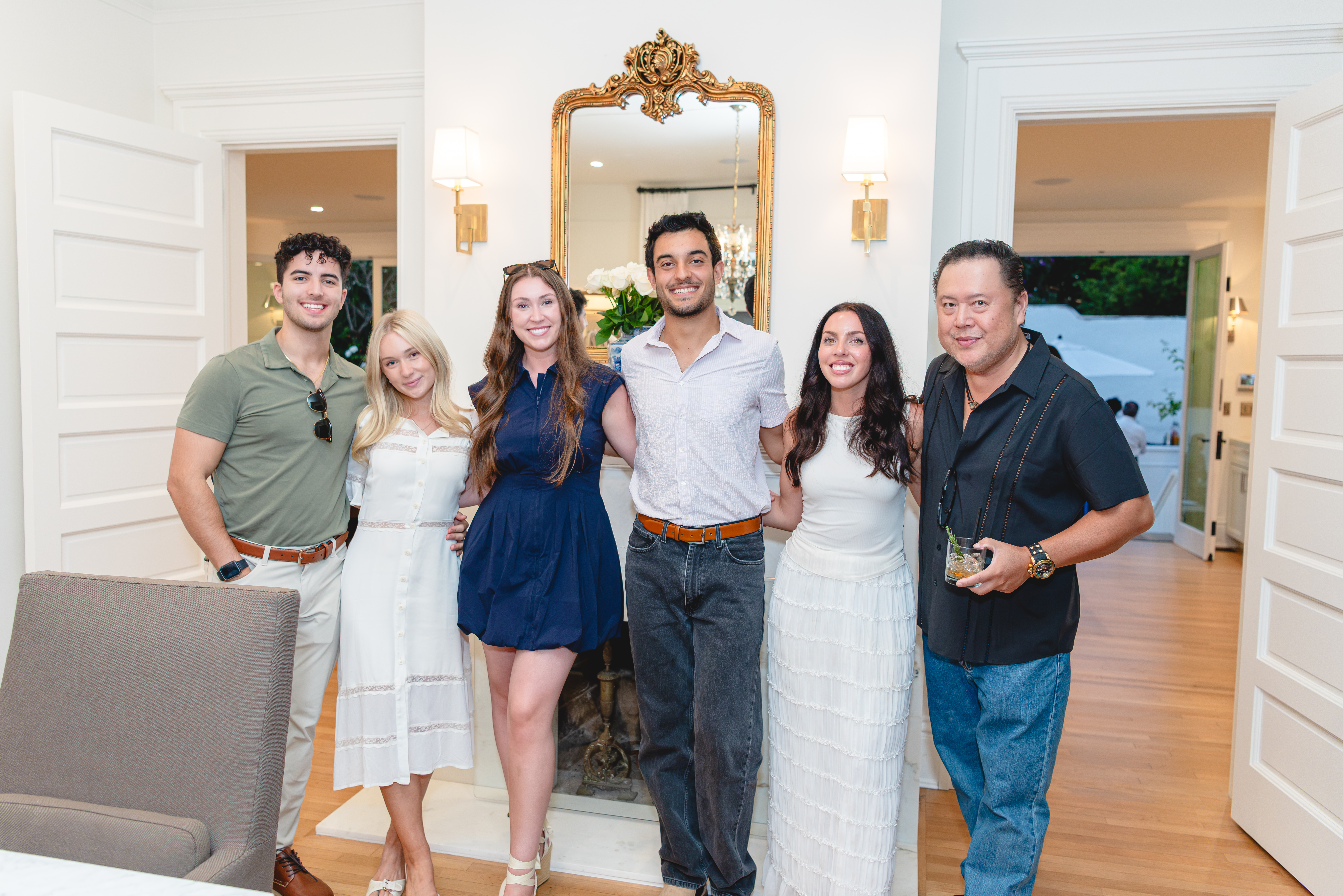 Group of guests posing in front of a gilded mirror