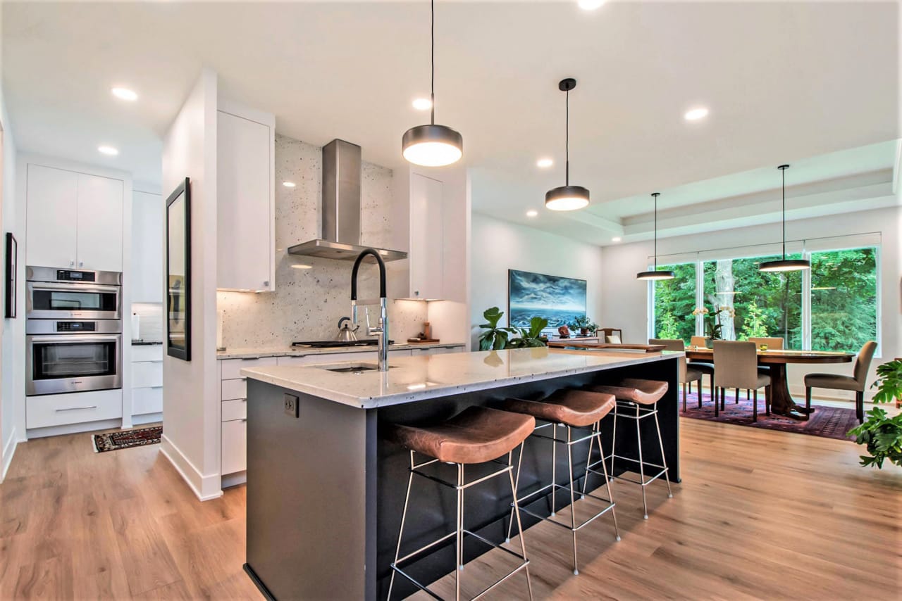 A kitchen with a large island and stools and with granite counter top