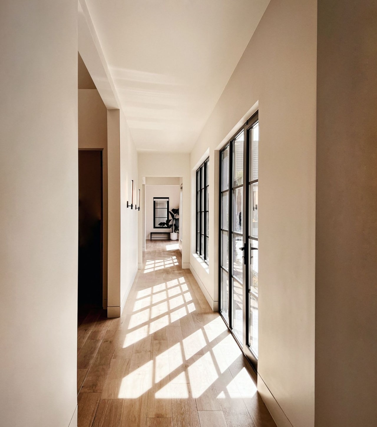 A long hallway with wooden floors and large windows along one wall.