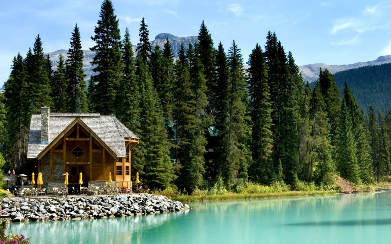 A cabin sitting on the shore of a lake surrounded by trees.