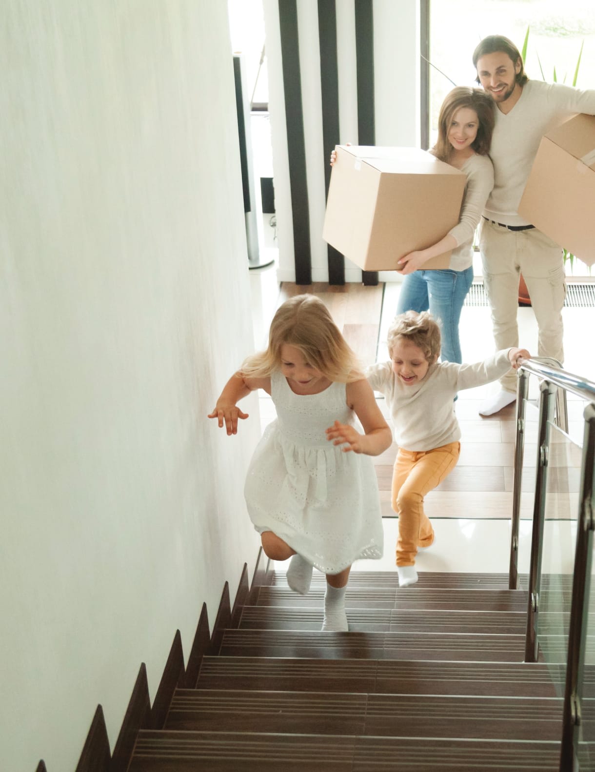 A family moves into a bright home as two children run down the staircase.