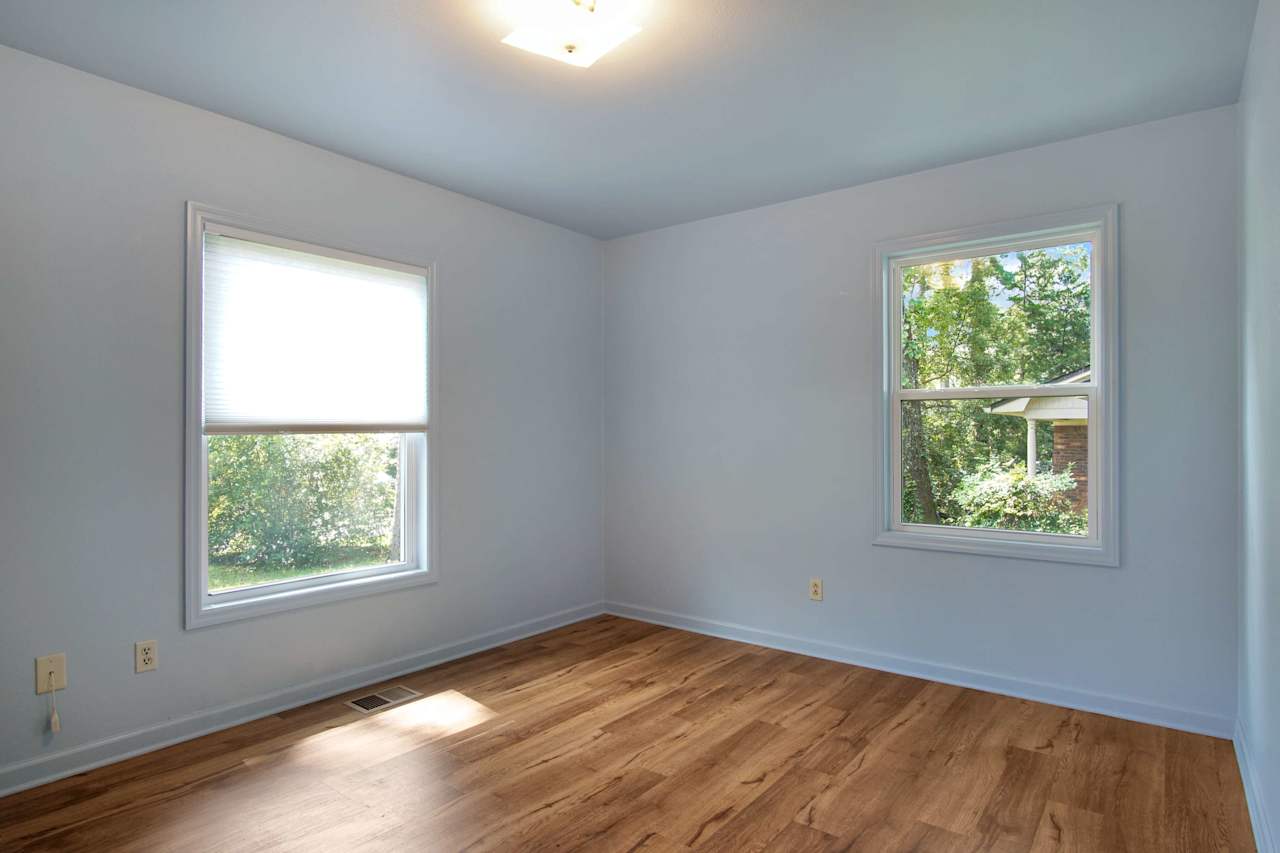 photo of third bedroom featuring lightly colored walls, 2 windows, rich plank flooring, and a simple light fixture at 1228 Winifred Drive, Tallahassee, Florida 32308