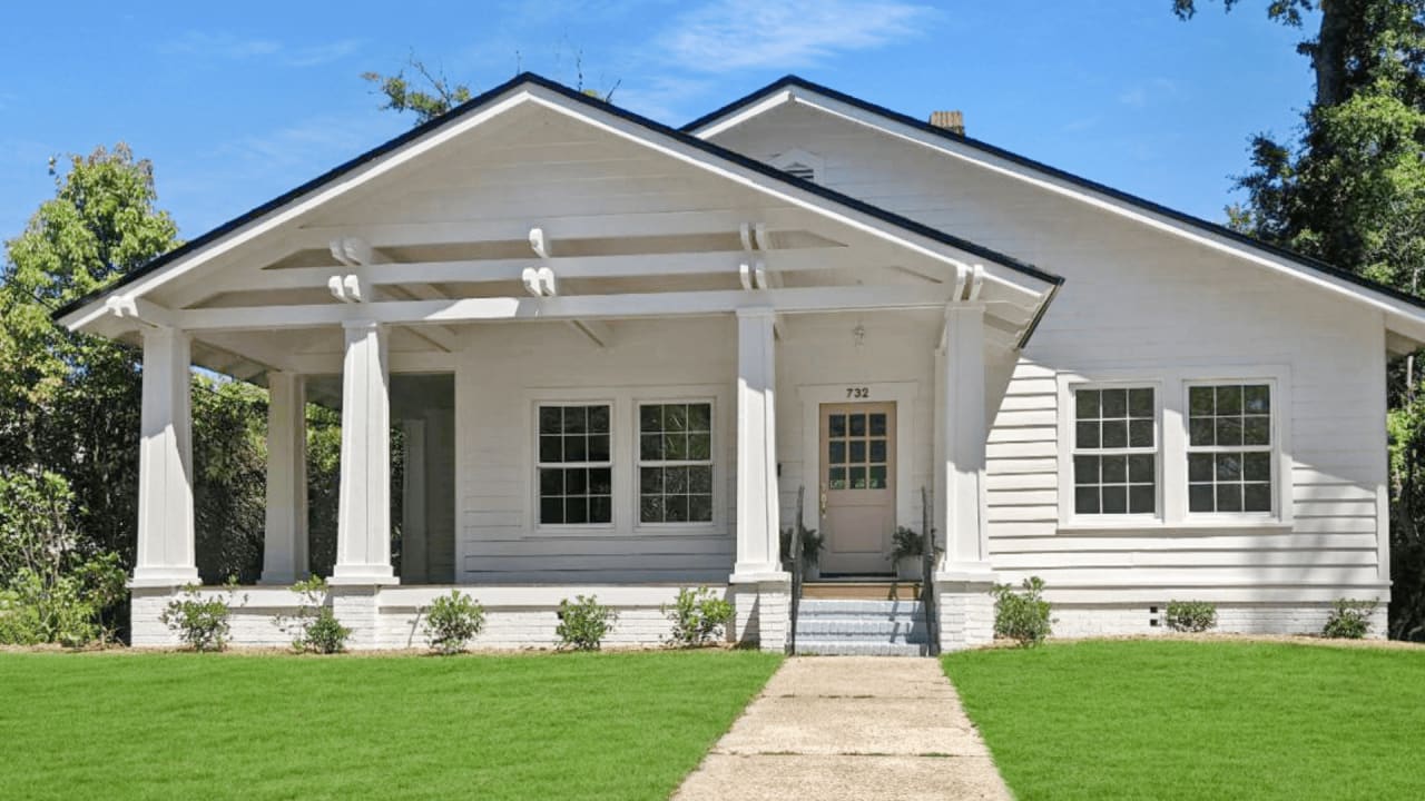  front view image of a white single-story house with a manicured lawn and a clear blue sky.