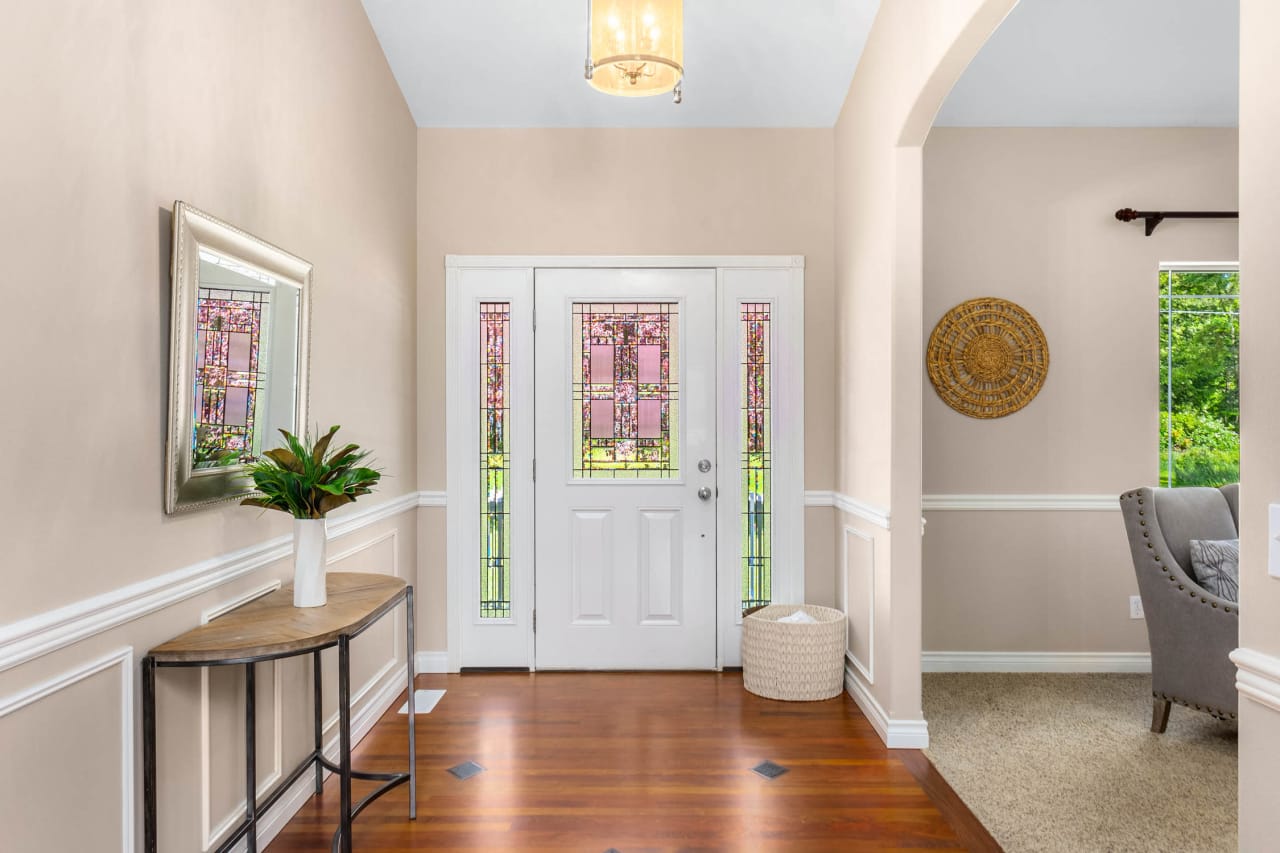 A bright and airy entryway with a wooden console table, a mirror, and a plant