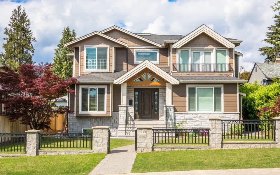 A two-story house with a brown exterior and a stone foundation