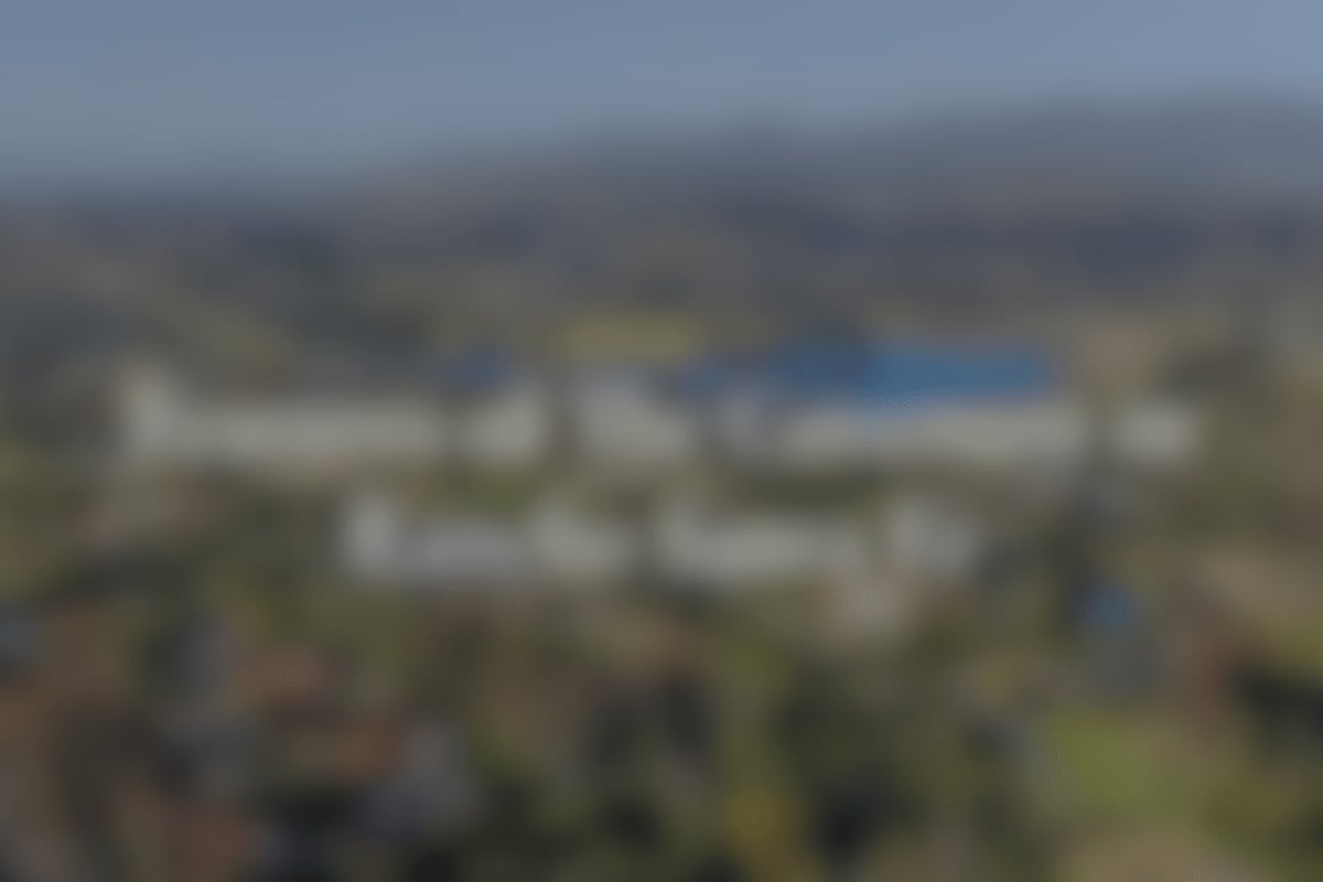 A blurred-out image featuring an overview of the golf course and other key amenities with a Discover More button overlay.