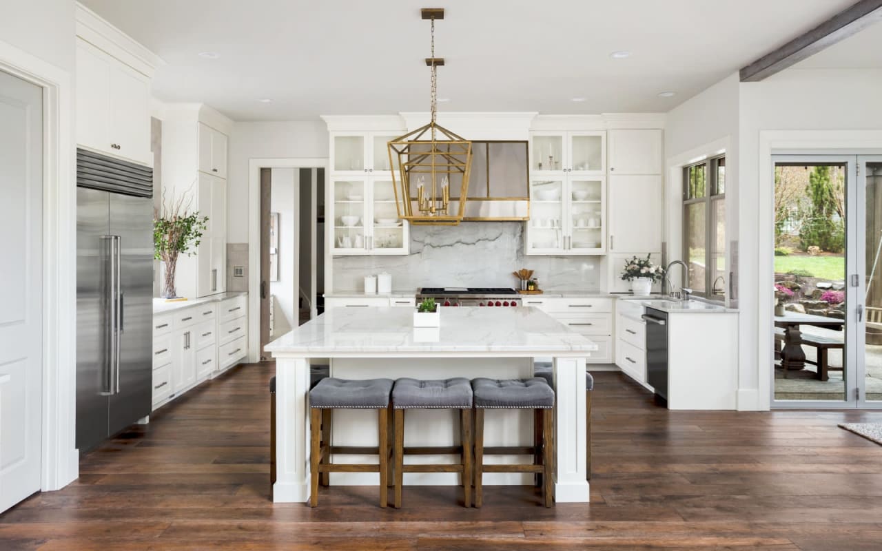 A kitchen with a large island in the middle, stools, and a stove