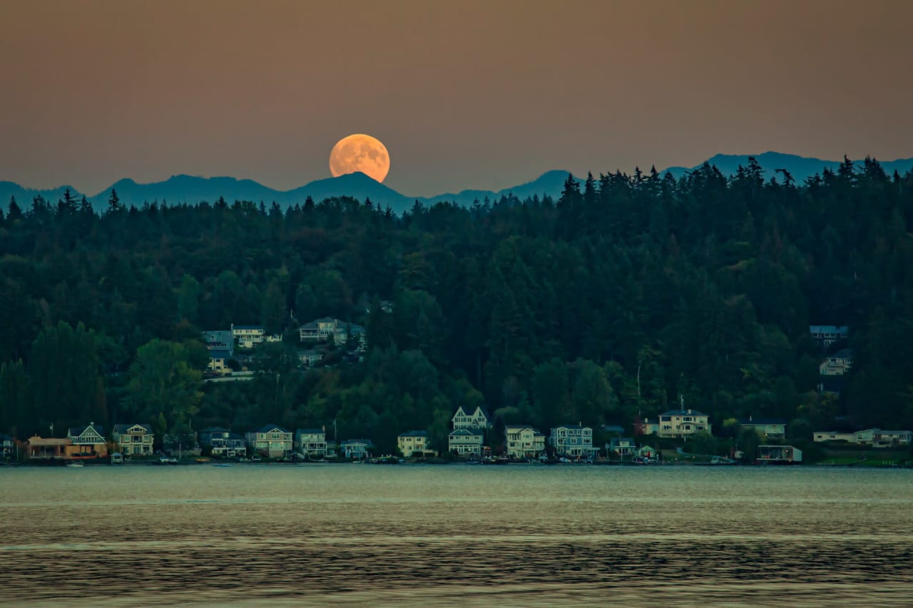 A full moon rising over a mountain range