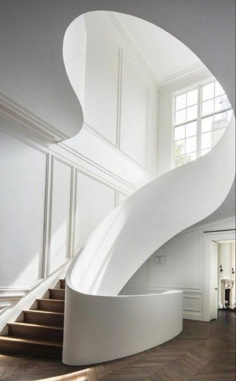 A dramatic, curved white staircase dominates a sleek and minimalist interior.