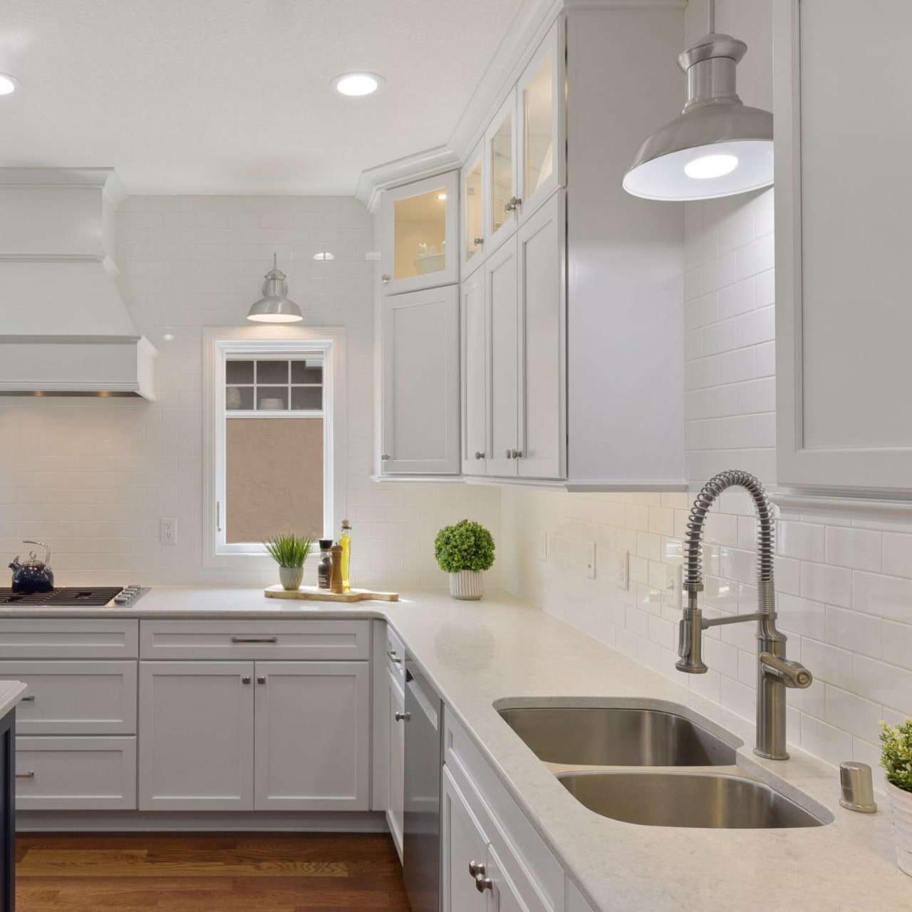 A kitchen with white cabinets, a stainless steel sink, and a window.