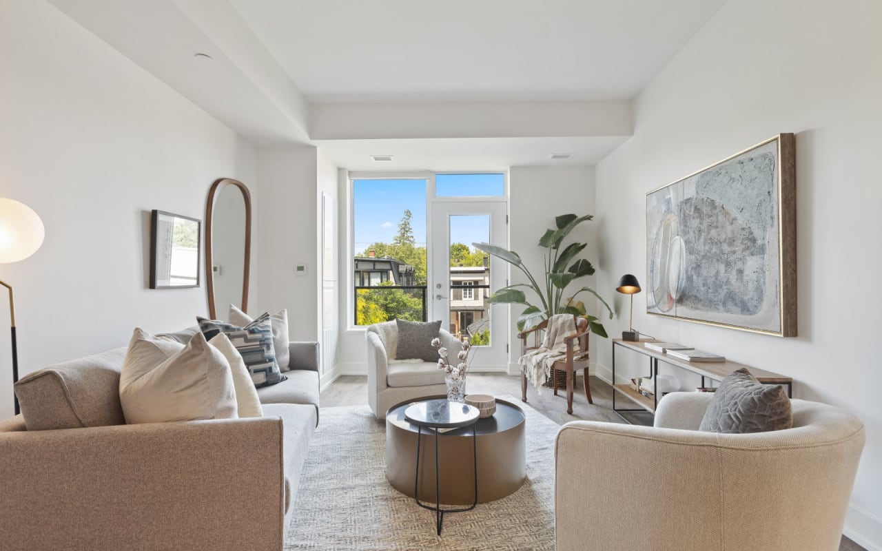 A living room with a couch, two chairs, a coffee table, and a painting on the wall.