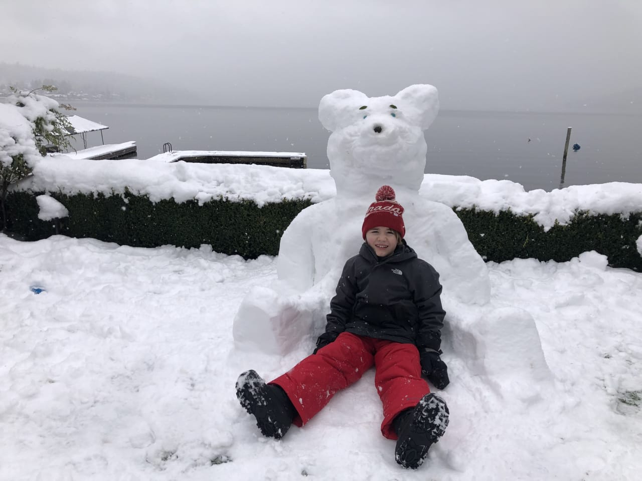 a kid sitting on a snowbear in a winter day