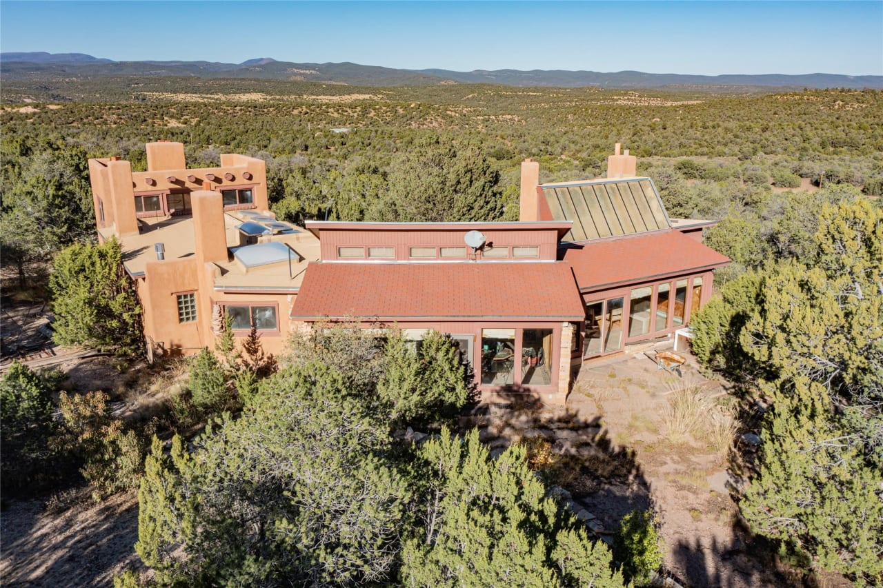 A large brick house in the center of a wooded area.