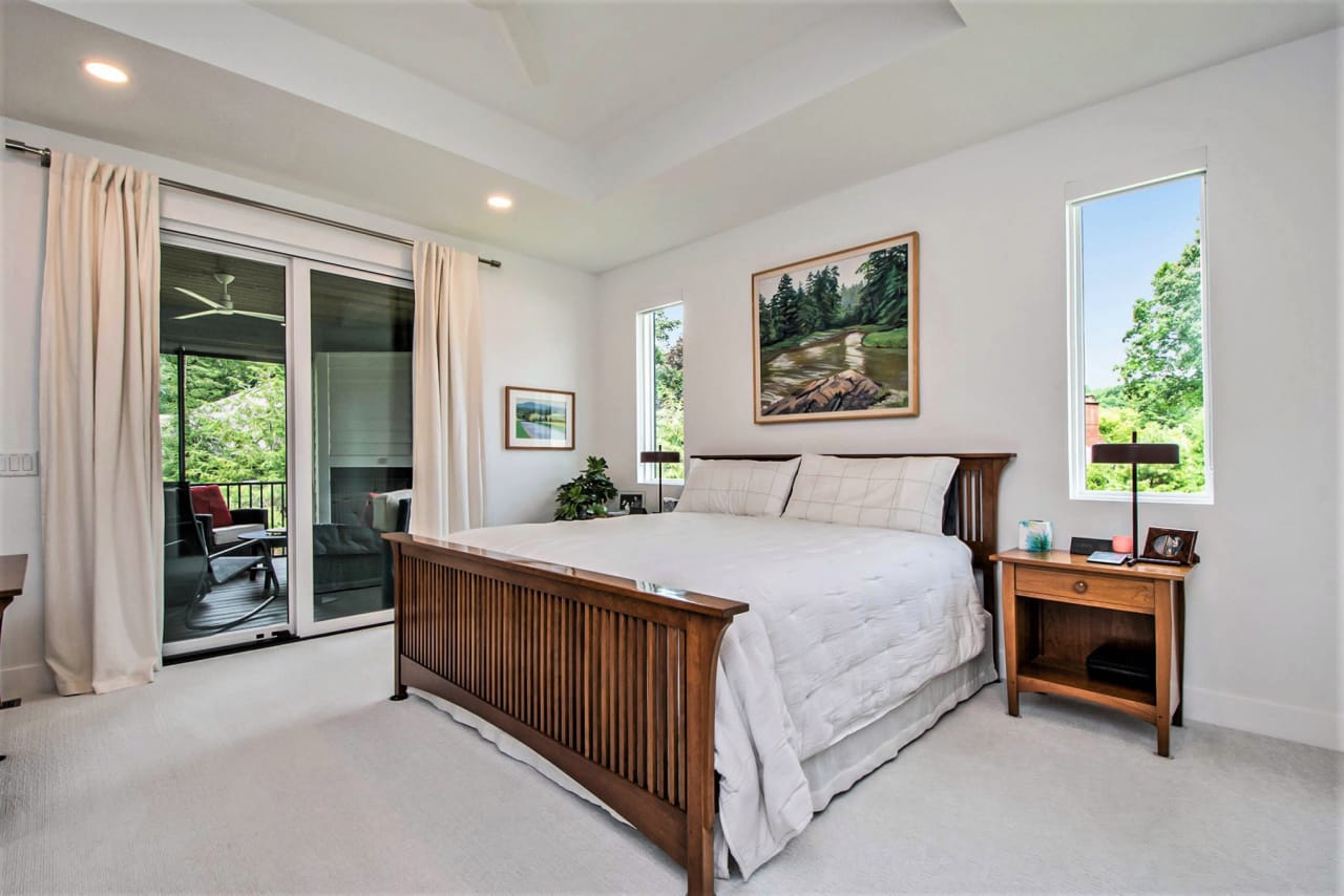 A bedroom with a bed, nightstand, and sliding glass door