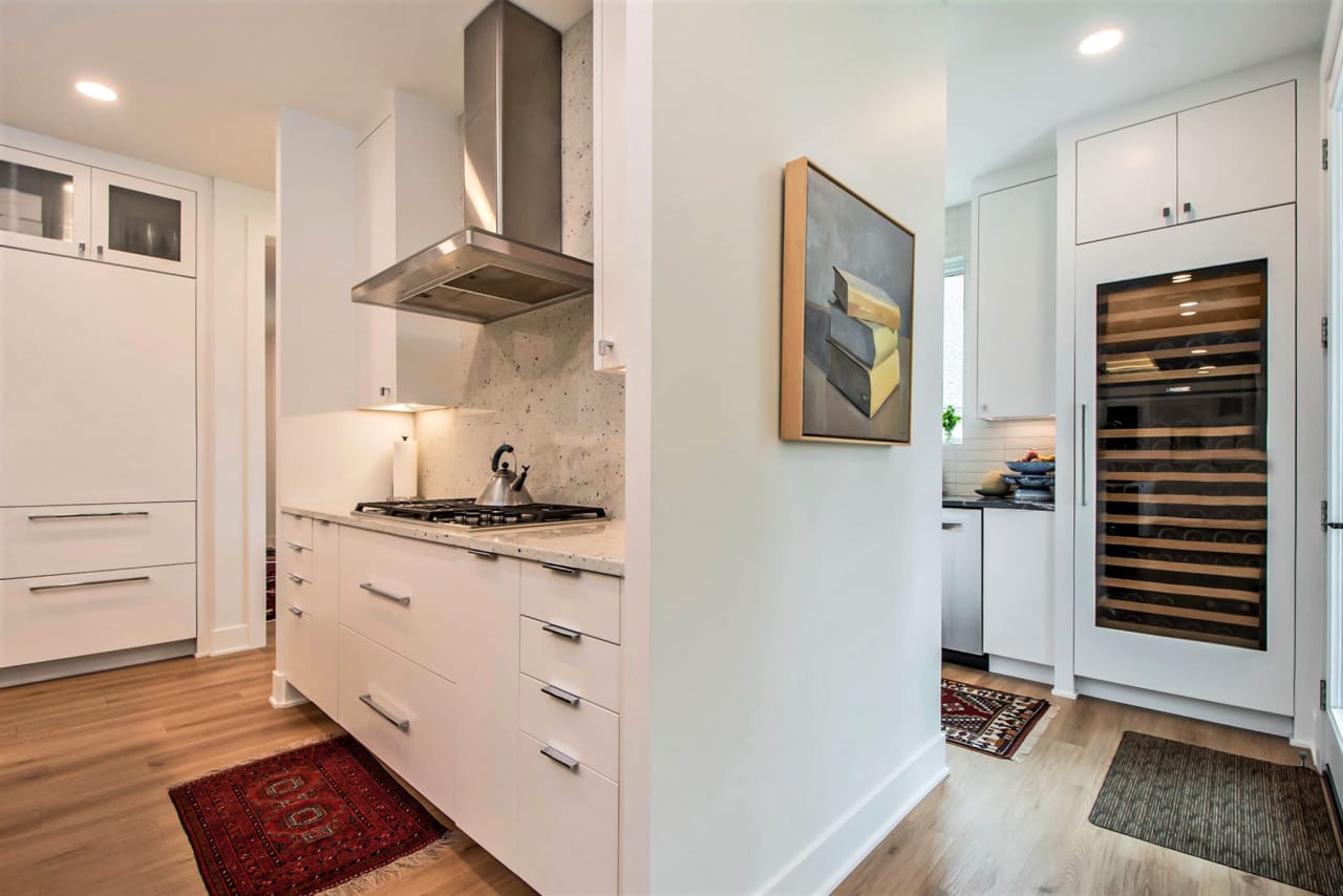 A kitchen with white cabinets and stainless steel appliances, and with wall frame