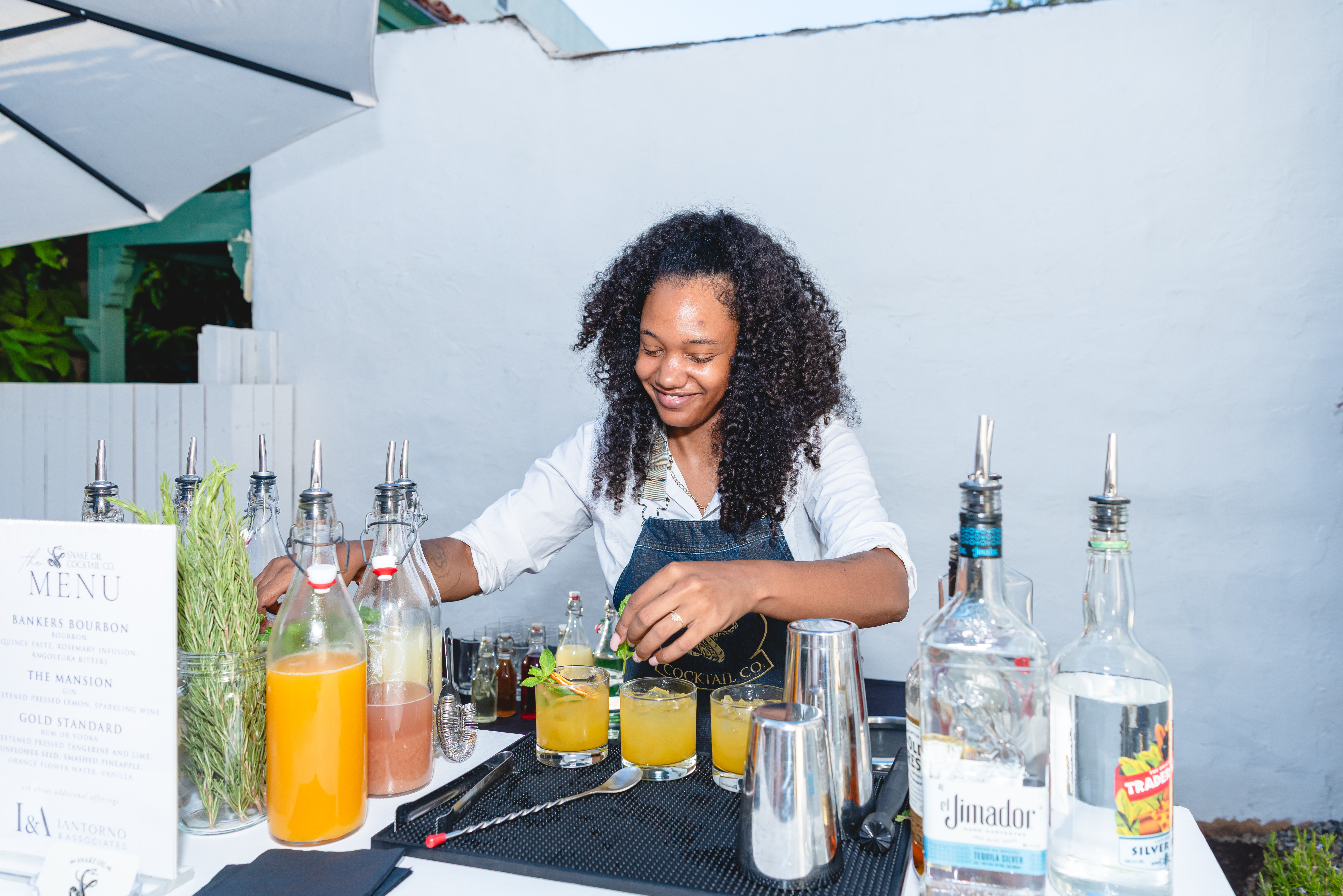 Bartender from Snake Oil Cocktail Co. mixing drinks beside the personalized cocktail menu