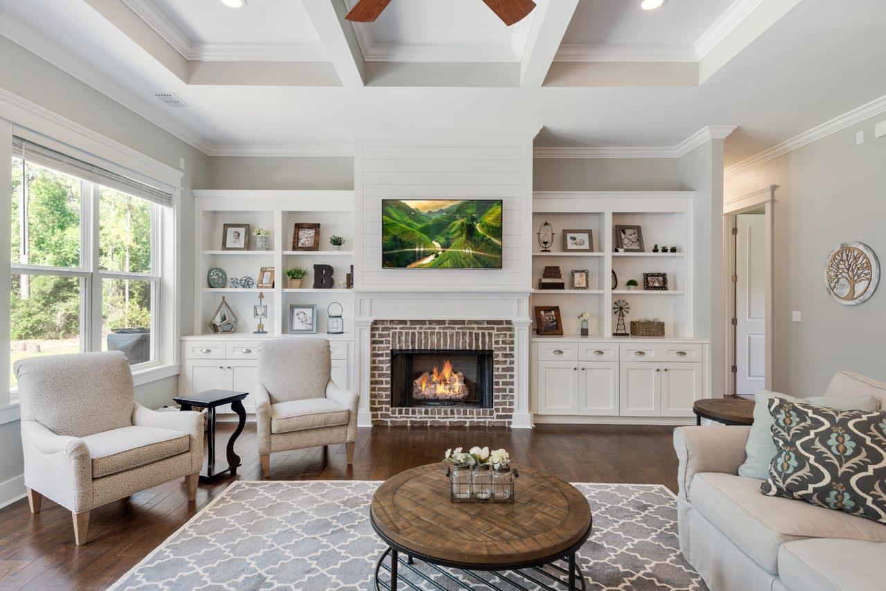 An interior view of a stylish living room with light-colored walls, built-in shelving, a fireplace, and comfortable seating. The room is well-lit and decorated with contemporary furnishings.