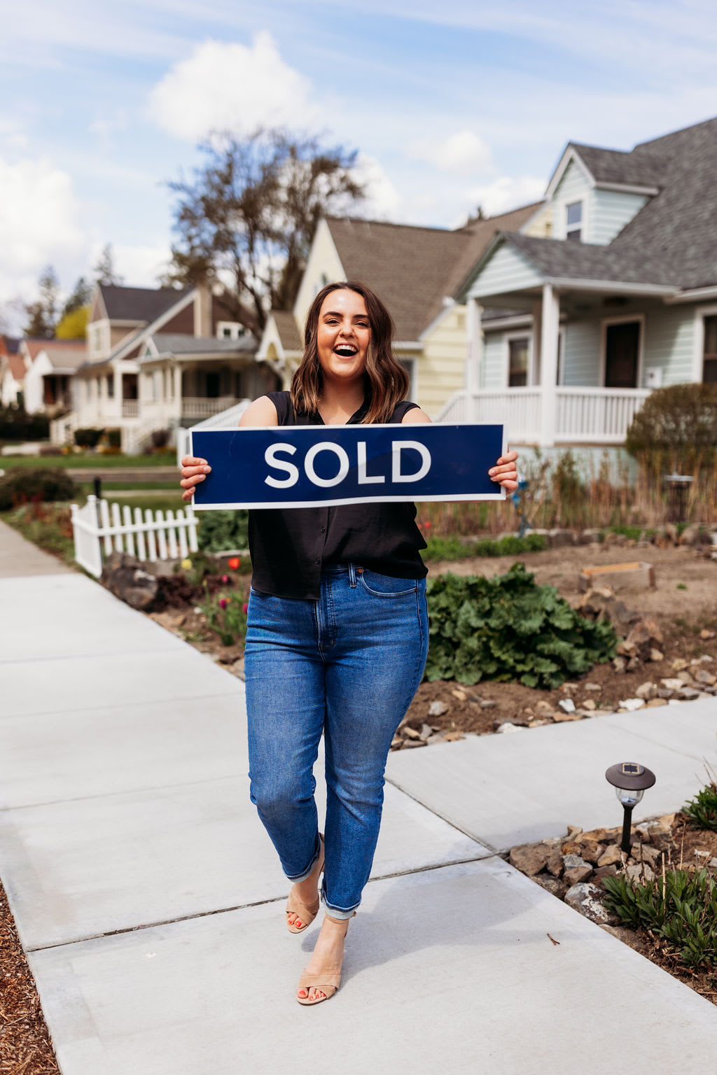 Samara Behler holds a sold sign in front of a home in Spokane, WA