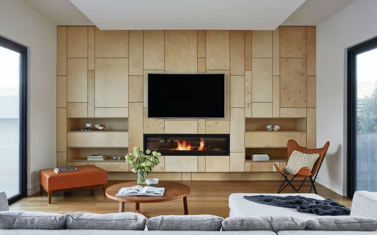 A living room with a fireplace and a flat-screen TV mounted on the wall.