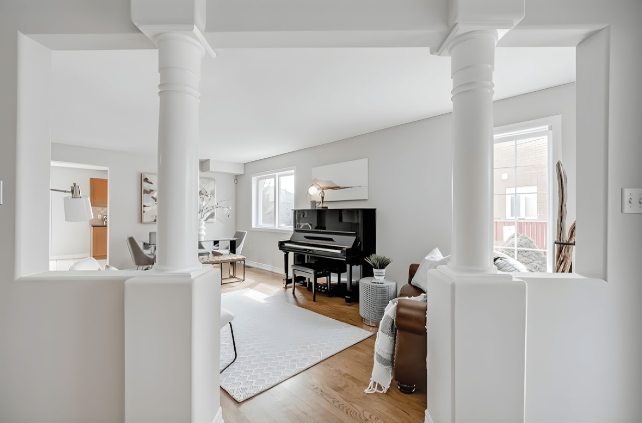 A living room with a grand piano in the corner and a dining table at the back.