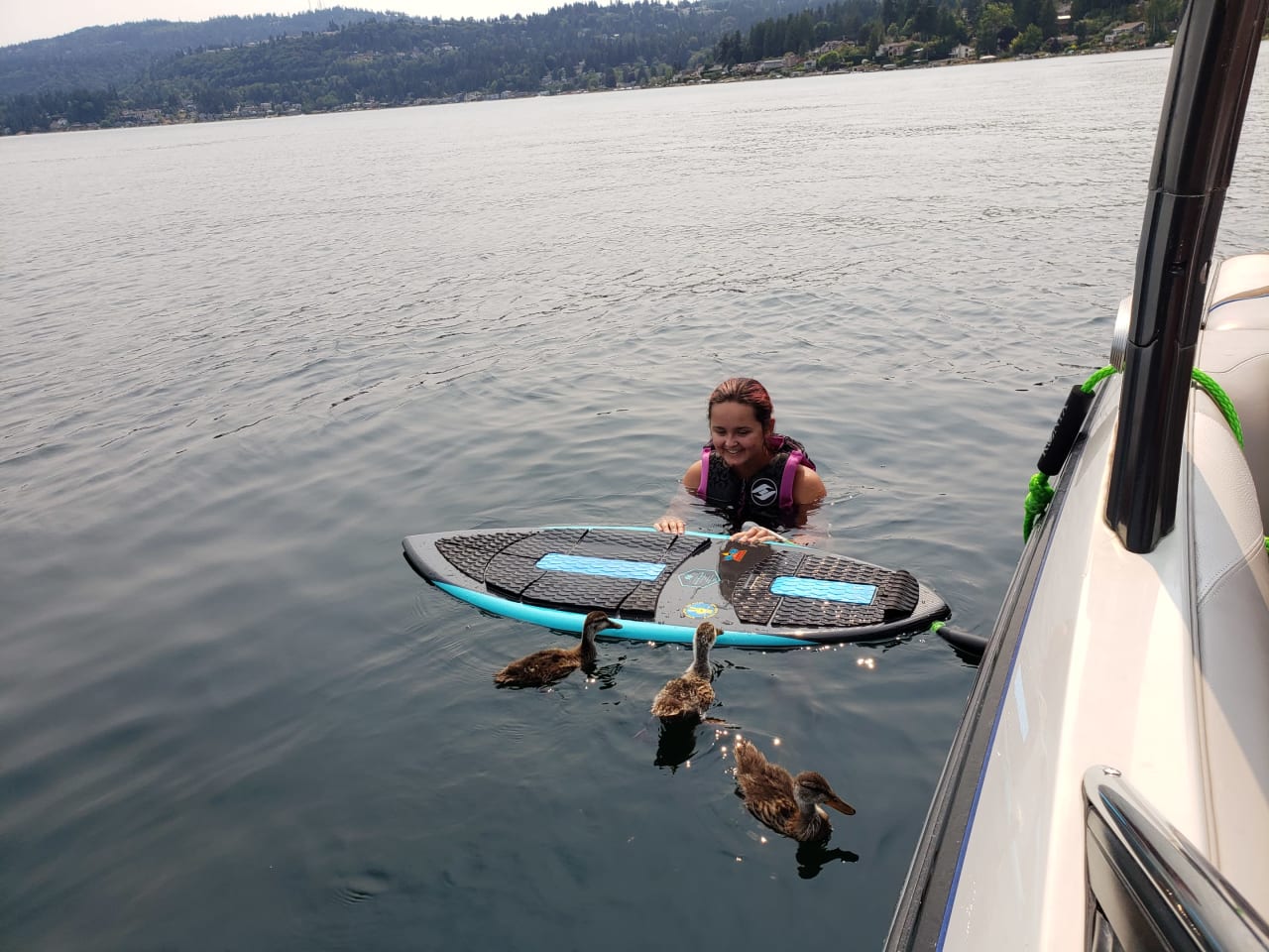 a kid swimming on a lake playing with a duck