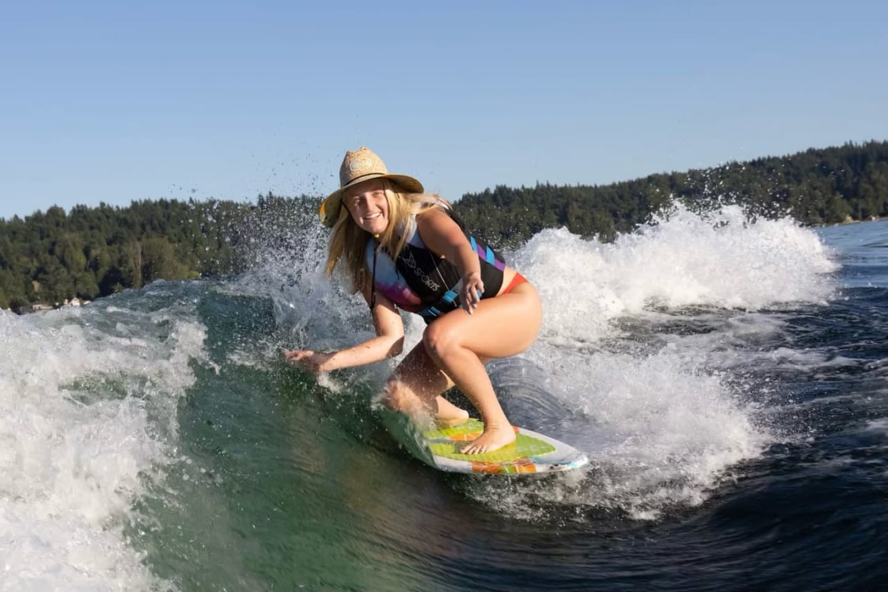 a lady wearing a cowboy hat riding a surfboard