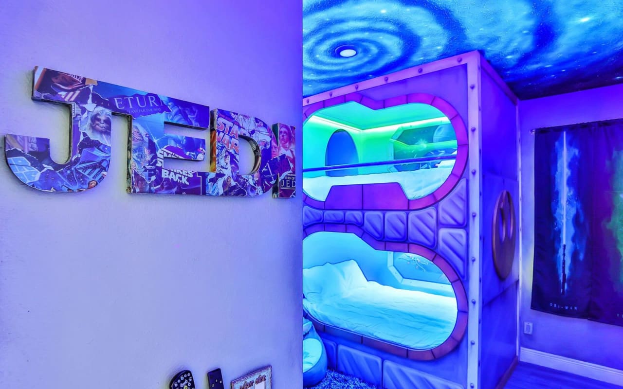 A bedroom interior with led lights on the bunk beds and a JEDI sign mounted on the wall