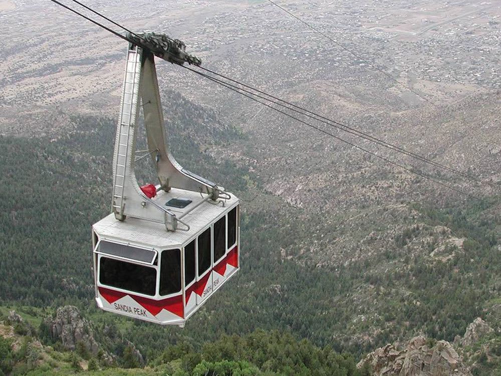 A red and white cable car ascending a mountainside.