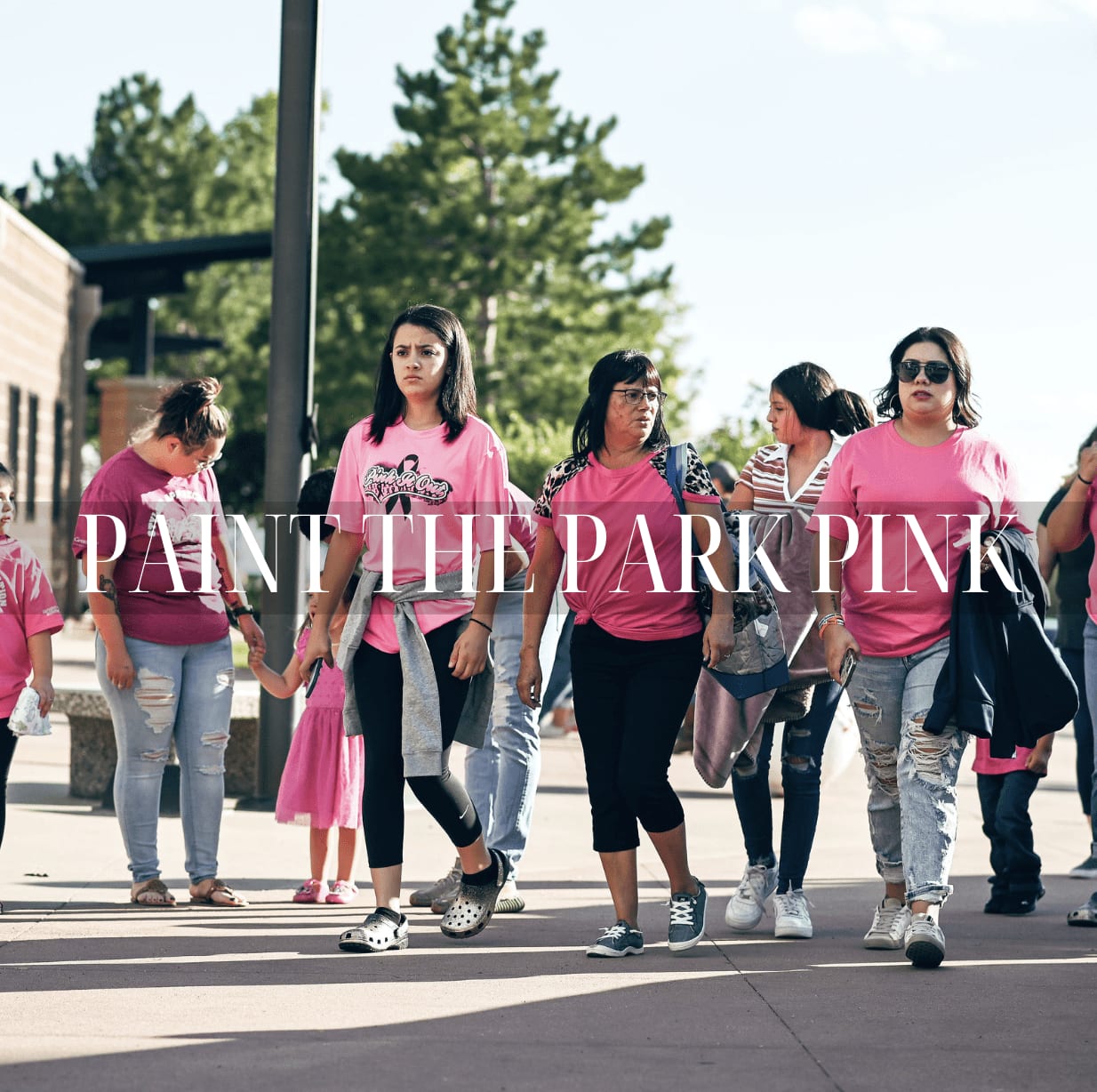 Group of women walking together wearing pink shirts. Text overlay reads 'Paint the Park Pink.