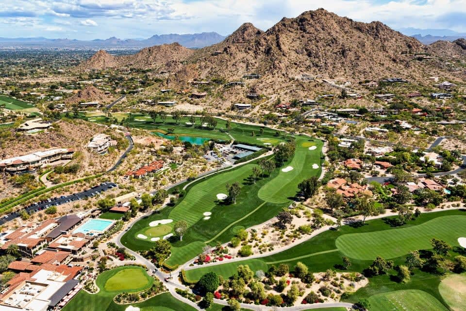 An aerial view of a golf course surrounded by mountains