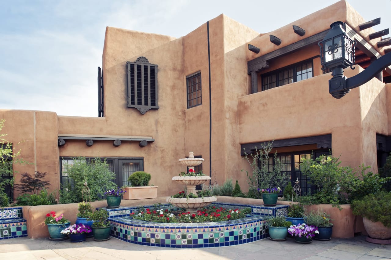 A traditional adobe building with a fountain in front of it.