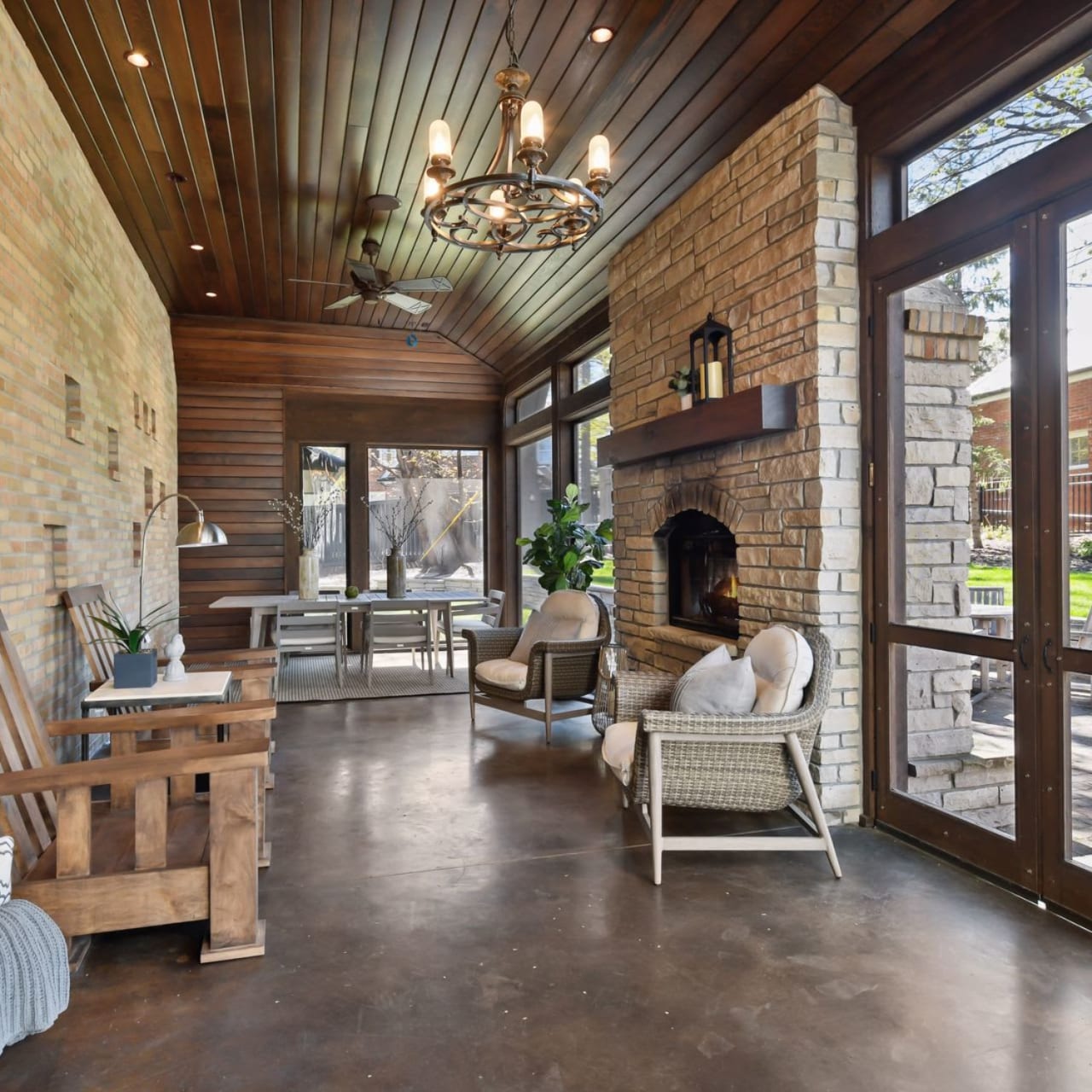 A screened-in porch with a stone fireplace in the corner.